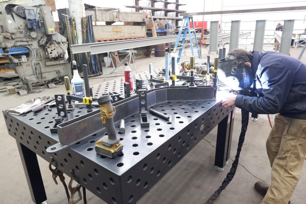 Sparks fly as an expert welder works at the work the table in the C G Fabrication shop.