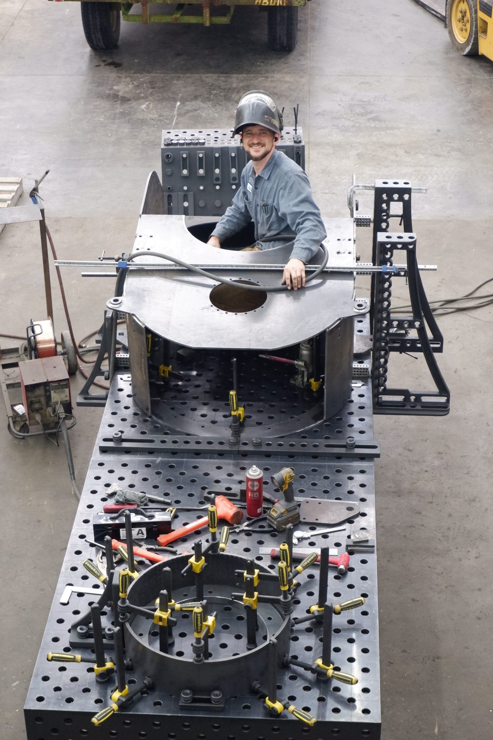 A CGF employee looks up from his welding project with a friendly smile. The team is positive and energized. Contact us to schedule your project.