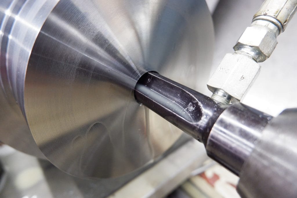 Boring bit drills through a solid metal cylinder.