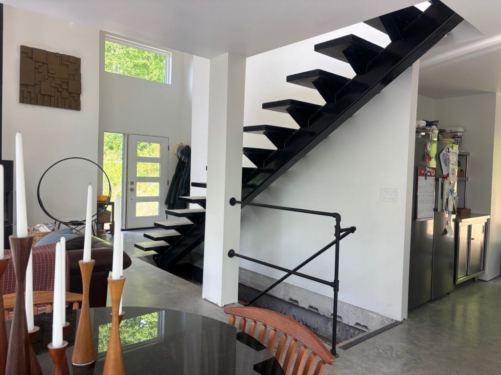 Custom black steel floating staircase with pipe railing, fabricated by C G Fabrication in Liberty, KY